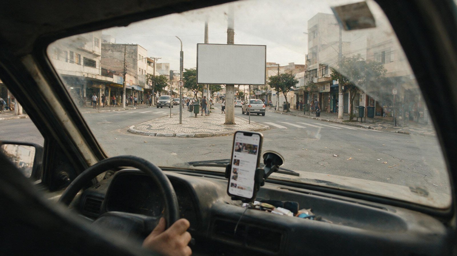 Motorista parado no sinal vendo um outdoor pela janela com o celular no painel — marketing online e offline integrado